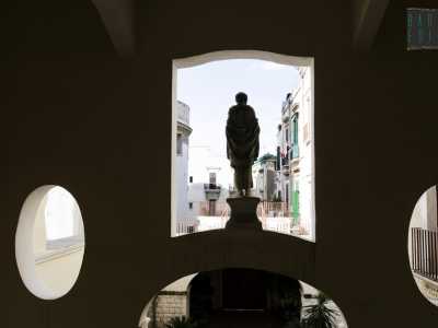 Gli edifici di Bari vecchia fanno da sfondo alla statua che si affaccia dal primo piano 